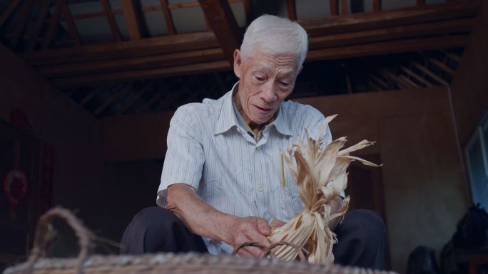 云南村庄里的老年农民用手剥玉米粒