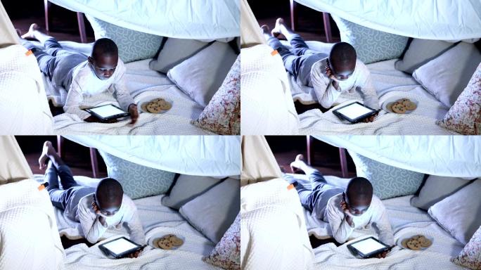 男孩在床上使用电子阅读器或平板电脑