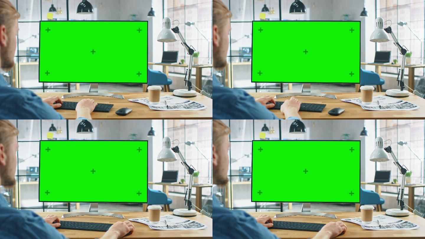 男子坐在带有绿色模拟屏幕的电脑前