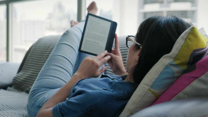 年轻女子在家沙发上放松阅读电子书