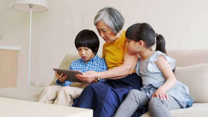 祖母给孩子们读书老年人陪伴晚年生活客厅沙