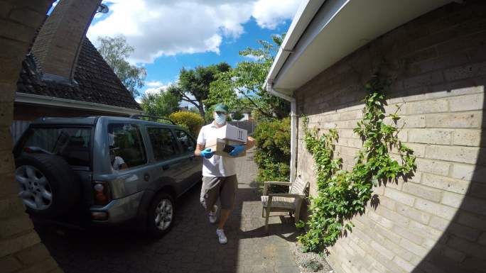 广角视角拍摄一名送货员到达一所房子。