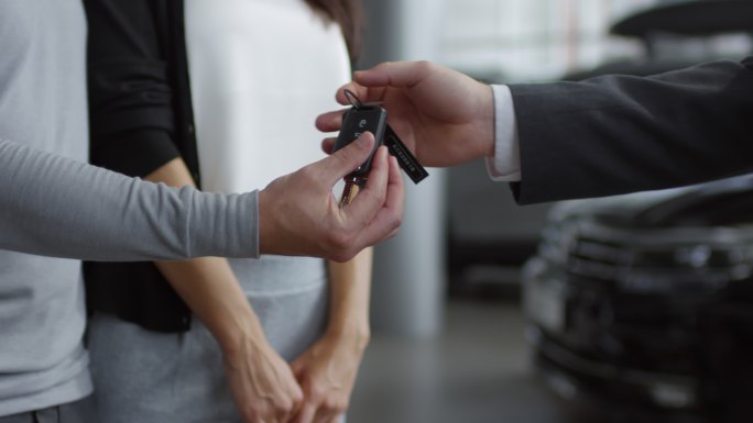 销售人员将车钥匙交给一对夫妇的手里