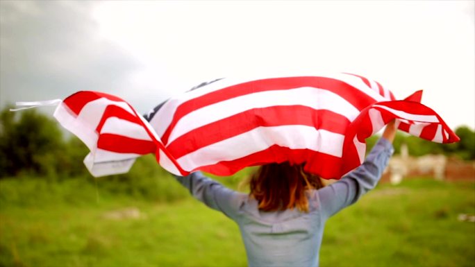 骄傲的美国女孩举着星条旗对着天空