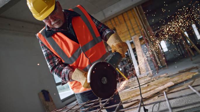 男建筑工人手持角磨机切割钢材