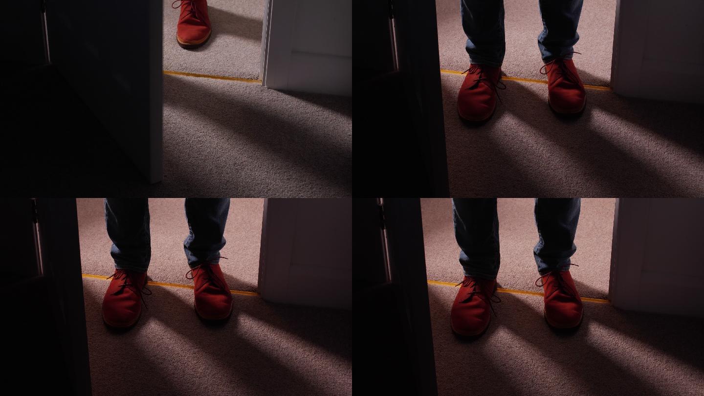 一名男子穿鞋进入黑暗房间的特写镜头。