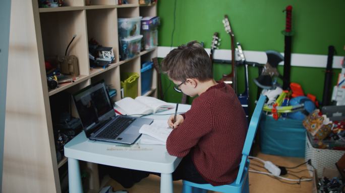 小男孩在房间里参加在线学校的课程。