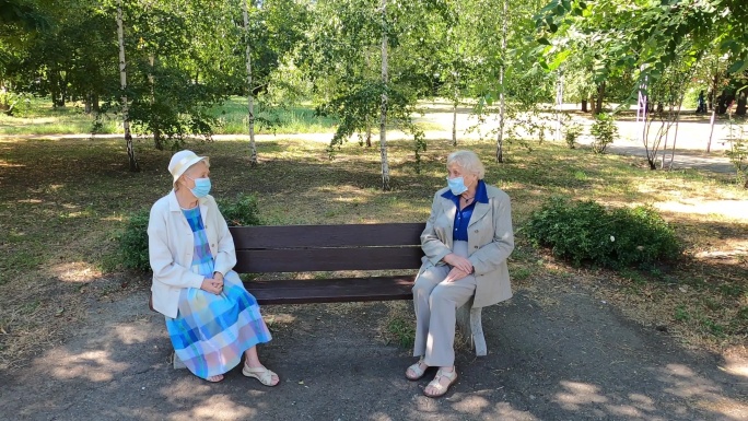 坐在公园里进行社交疏远的老年妇女。