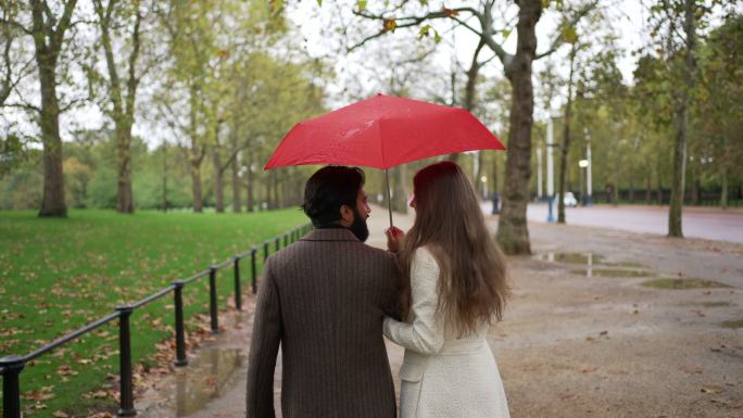 一对浪漫的年轻夫妇带着雨伞在雨中散步