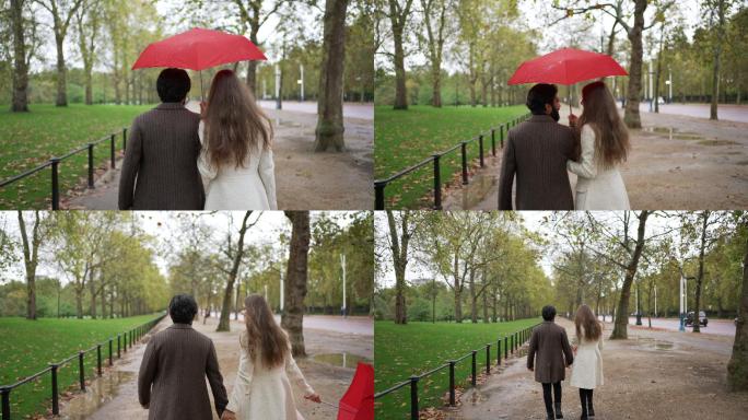 一对浪漫的年轻夫妇带着雨伞在雨中散步