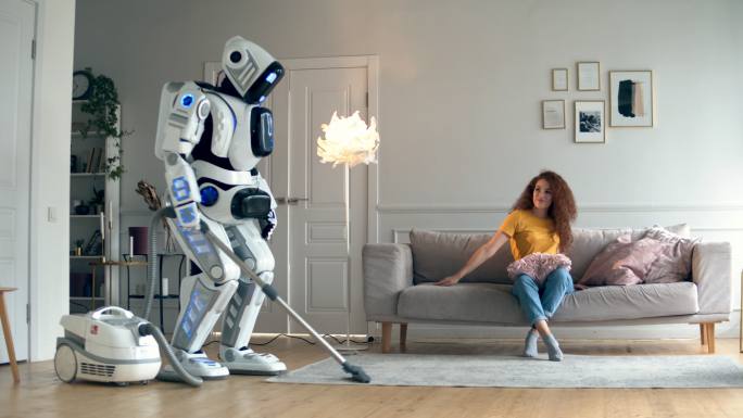 一个女人坐在沙发上，机器人在清理地板。