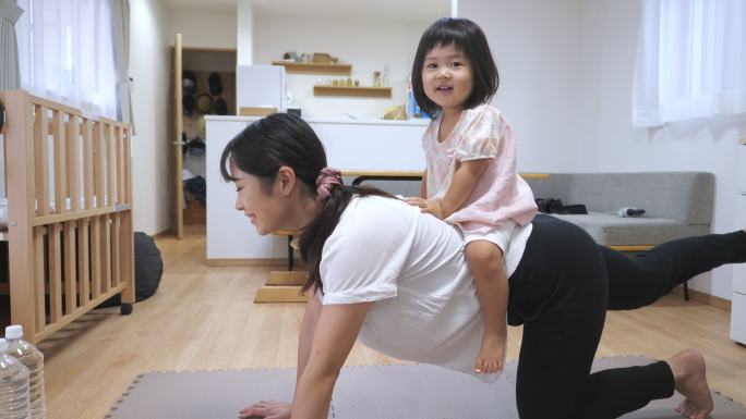 年轻的母亲和女儿在客厅里锻炼