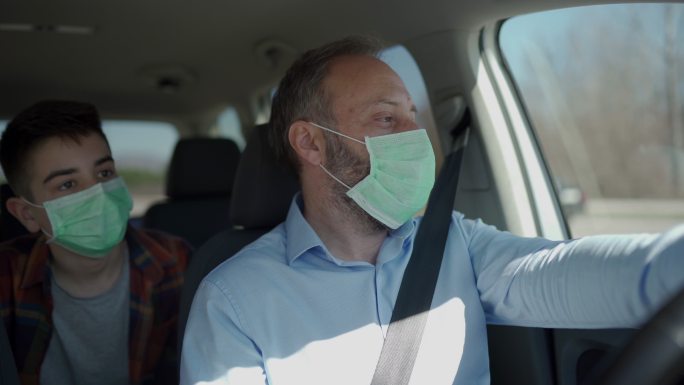 父亲和儿子戴着防护面具坐在车里