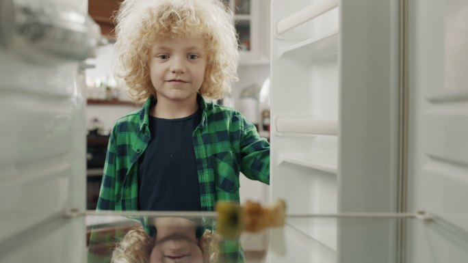饥饿绝望的男孩看着他的空冰箱