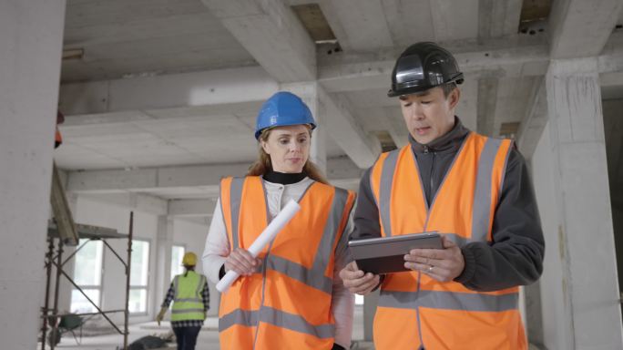 一位女士和一位男建筑师在建筑工地讨论。