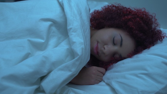 妇女睡在床上，盖上毯子，矫形床垫