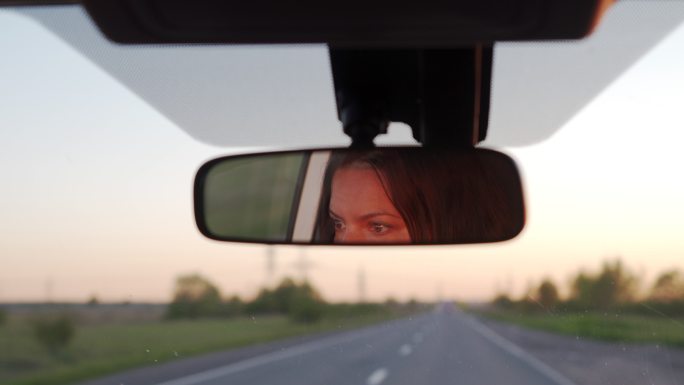 黄昏时分，车的后视镜映出了女子的脸