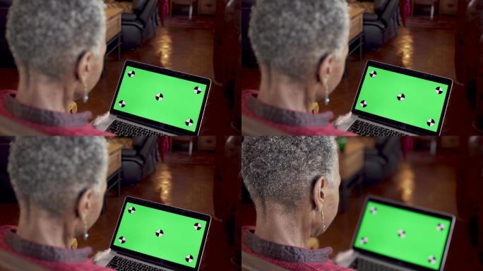 妇女一边看着绿色屏幕的电脑一边点头同意