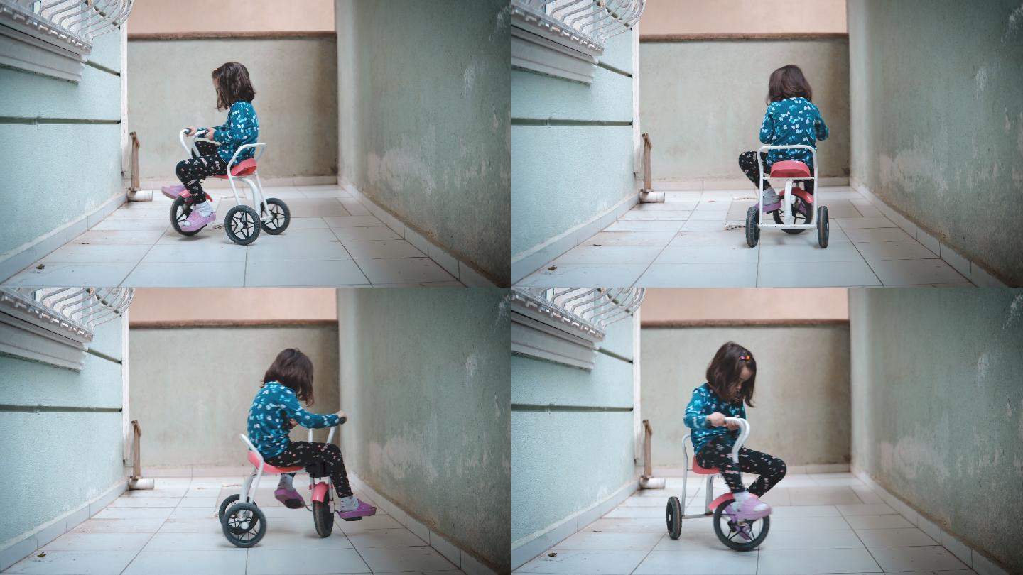 小女孩在阳台上骑三轮车。