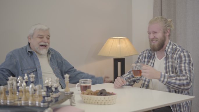 两个快乐的男子在室内笑着喝茶。