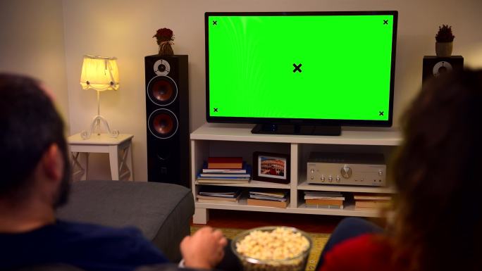 夫妇在家看彩色键绿色屏幕电视