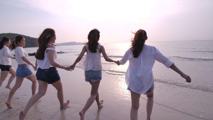 一群女性朋友日落时分在海滩上奔跑