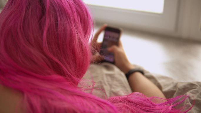 粉色头发的女孩在手机上聊天