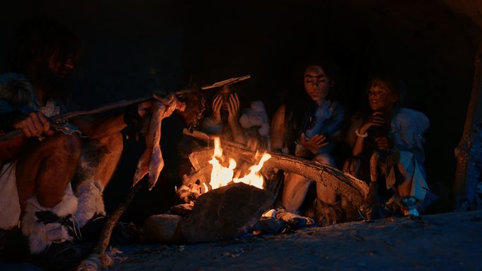 智人家庭在篝火上烹调动物肉