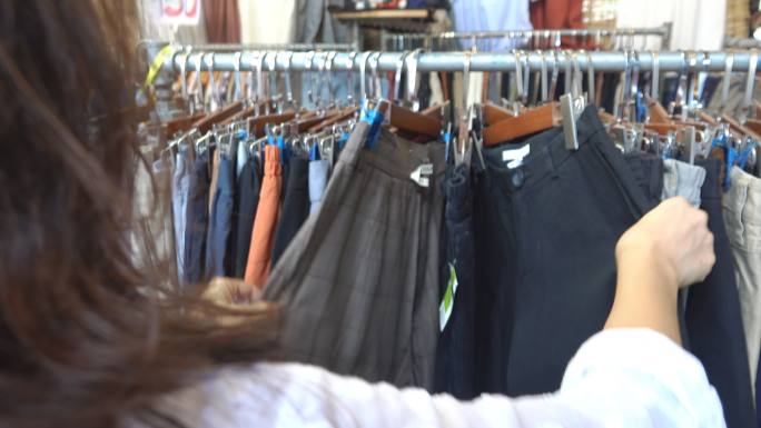 商店里的女人选择挂在货架上的牛仔裤