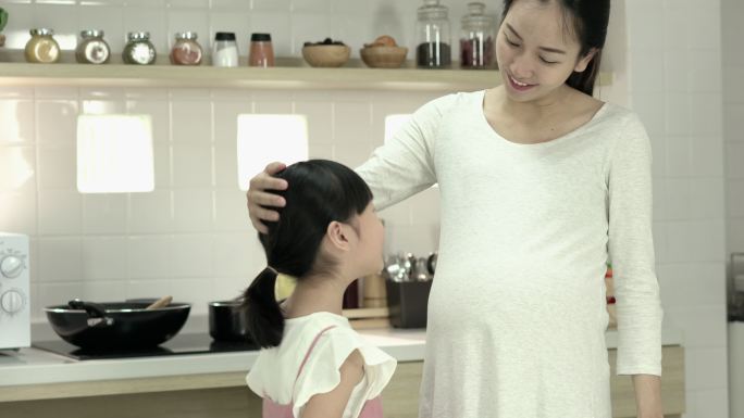 女儿和母亲拥抱二胎室内厨房妊娠期准妈妈