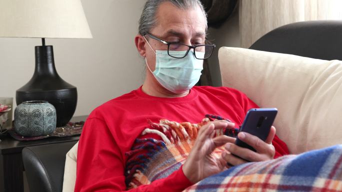 男人在家玩手机男人躺在沙发上在家养病病戴