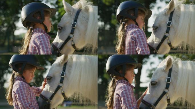戴着骑师头盔的可爱小女孩亲吻一匹白色小马
