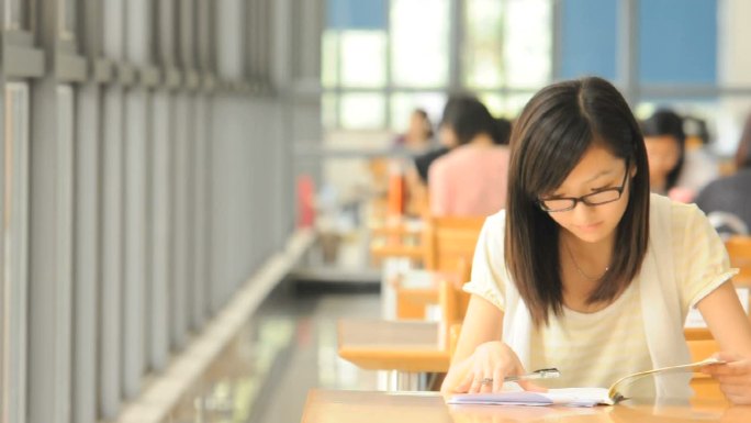 戴眼镜的女孩在大学图书馆学习