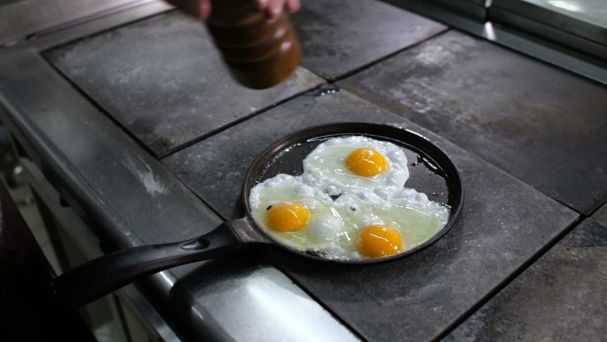 在煎锅里煎鸡蛋。早餐早点国外晚餐做饭做菜