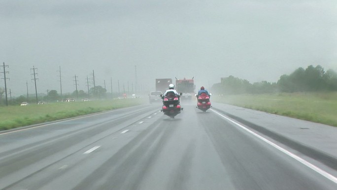 暴雨中两名摩托车手在高速公路上行驶