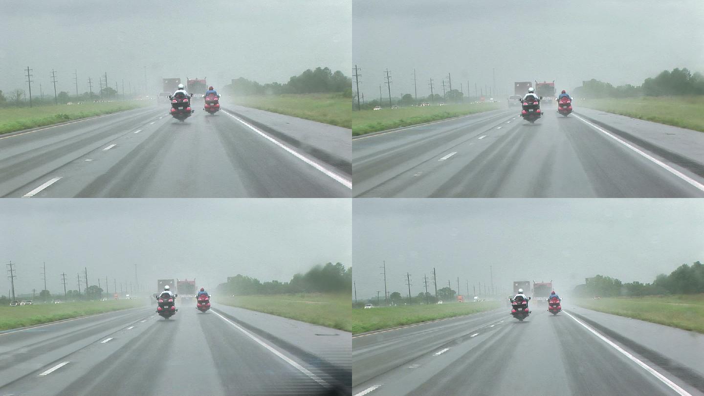 暴雨中两名摩托车手在高速公路上行驶