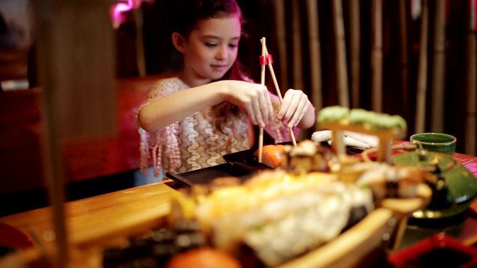 小女孩在一家日本餐馆尝试寿司卷
