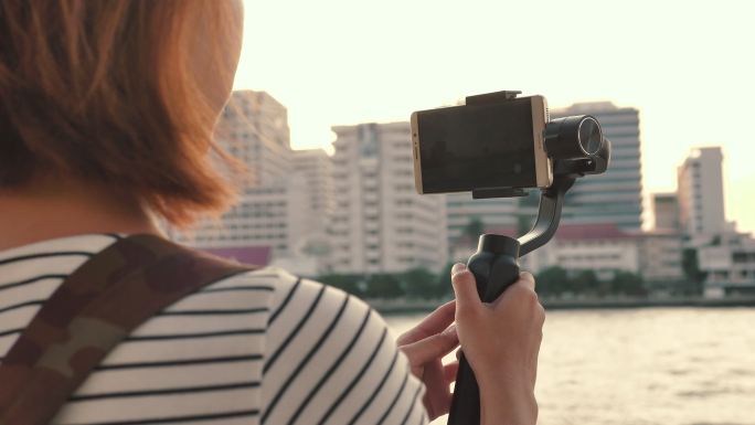 女人拿着智能手机拍河流