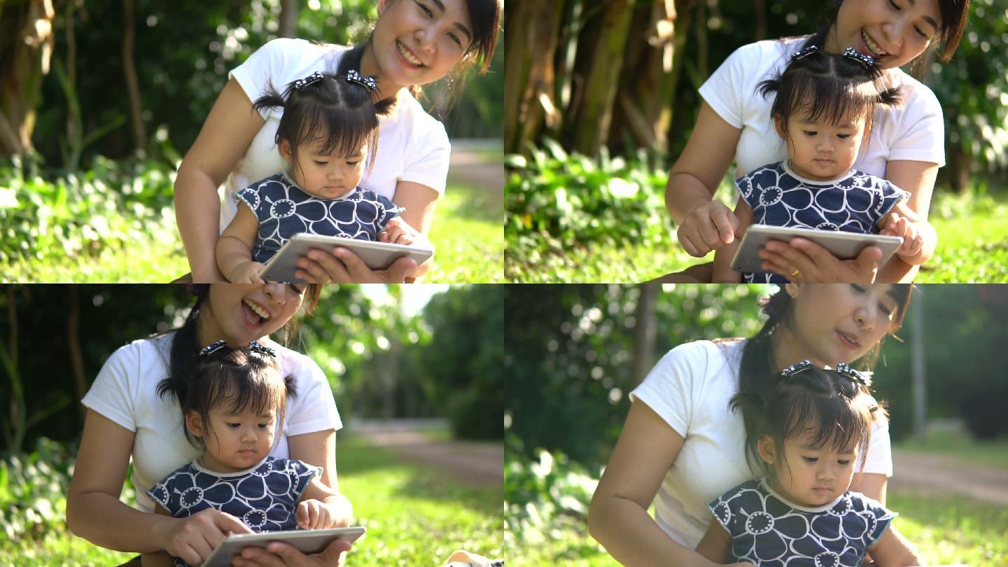 母亲在树下给女儿读一本书