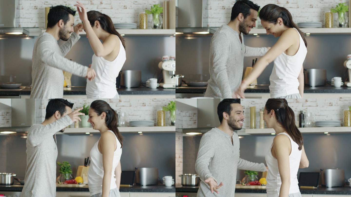 快乐的年轻夫妇在厨房跳舞，然后拥抱