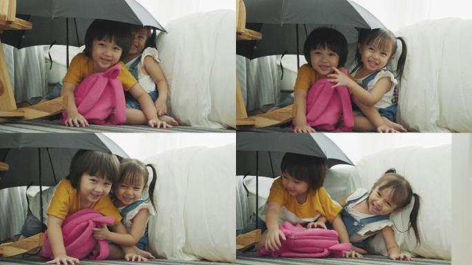 小朋友躲在雨伞下玩躲猫猫游戏