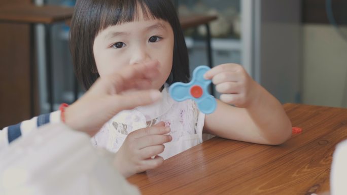 小女孩和妈妈在餐厅吃饭的时候玩玩具