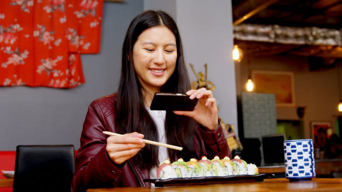 在4k餐厅用手机拍寿司的女人