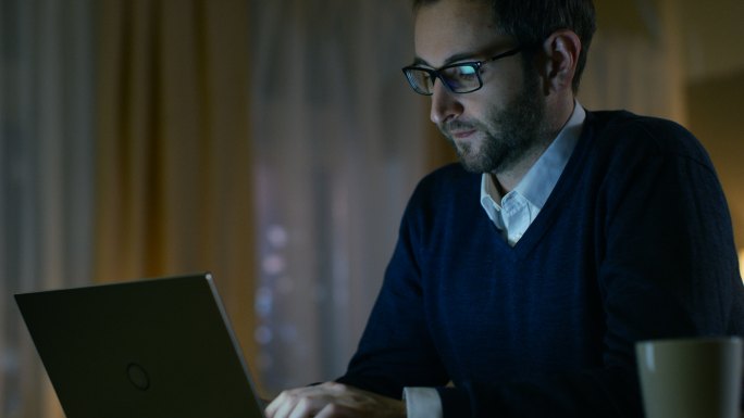 男子戴上眼镜开始在笔记本电脑上工作