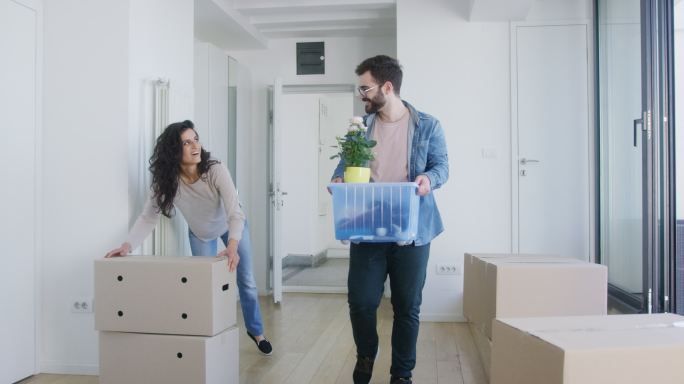 一对年轻夫妇搬着箱子搬进了新公寓。