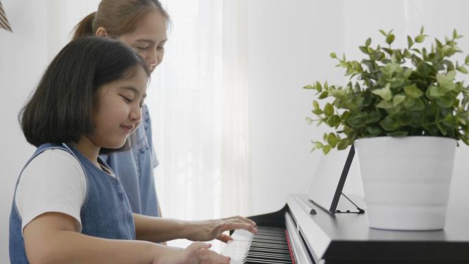 亚洲女孩和她的母亲弹钢琴