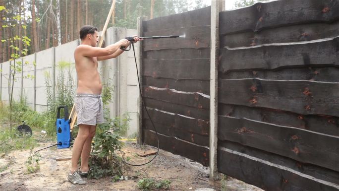 男人在清洗栅栏后院中年男士高压水枪