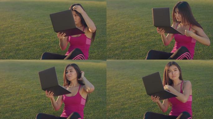 年轻女子坐在草地上看笔记本电脑