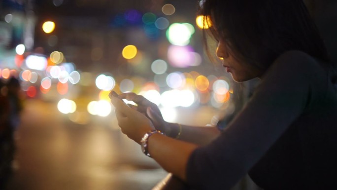 女孩在夜间街道上使用智能手机