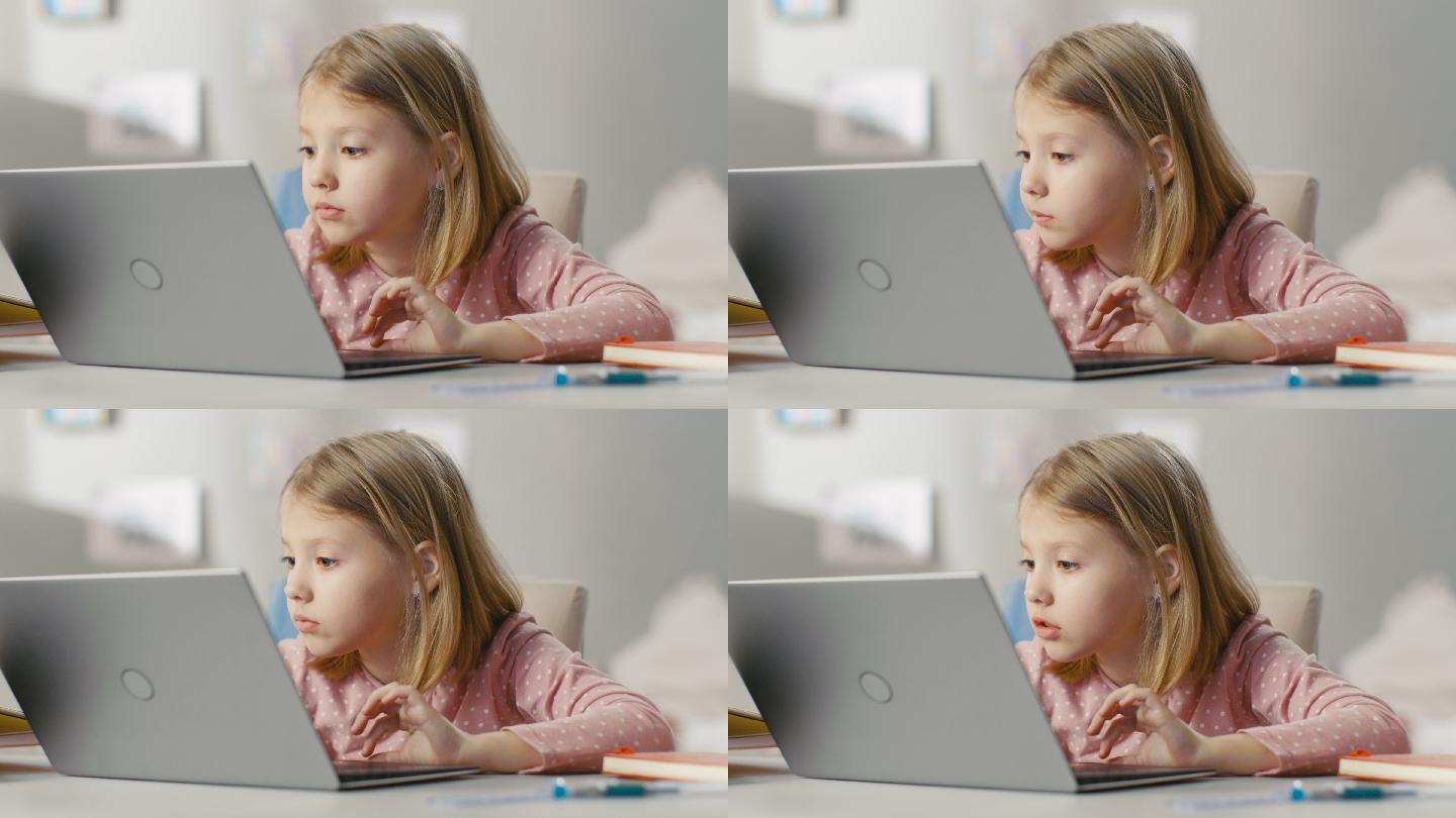 可爱女孩坐在她的桌子旁使用笔记本电脑